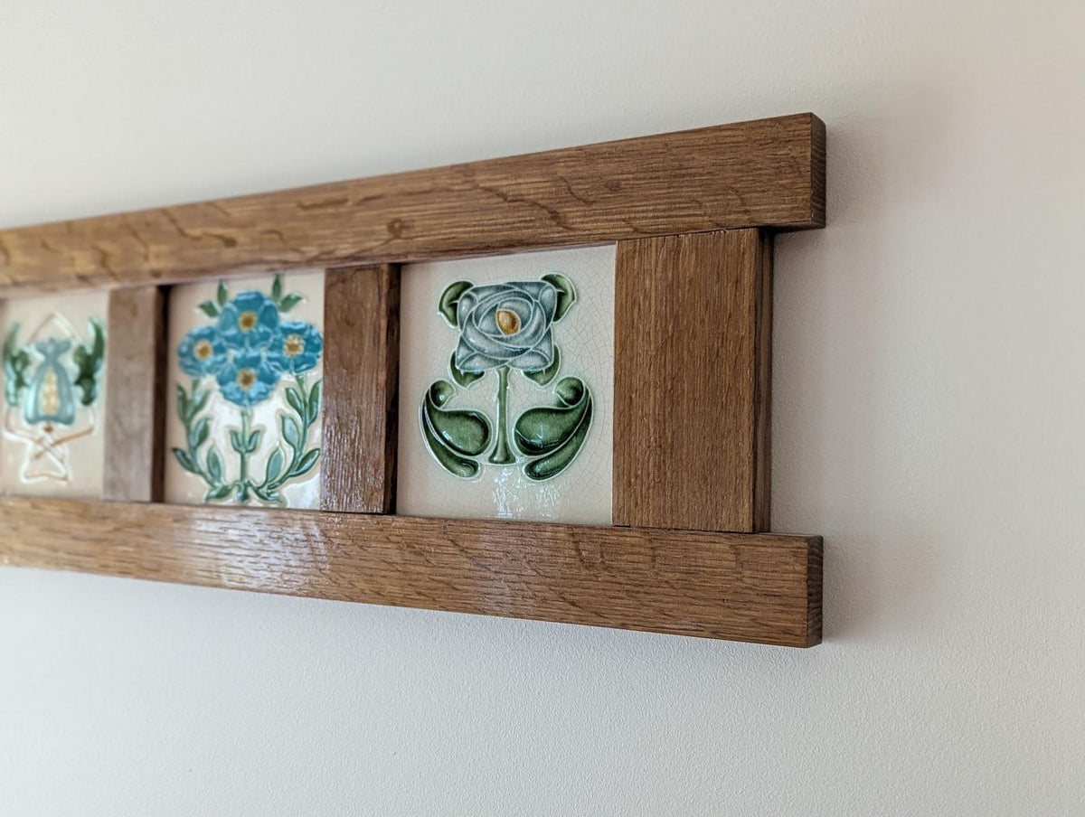 Handcrafted Arts and Crafts tile frame made from fumed quarter-sawn oak, displaying three decorative ceramic tiles with blue and green floral patterns on a white background.